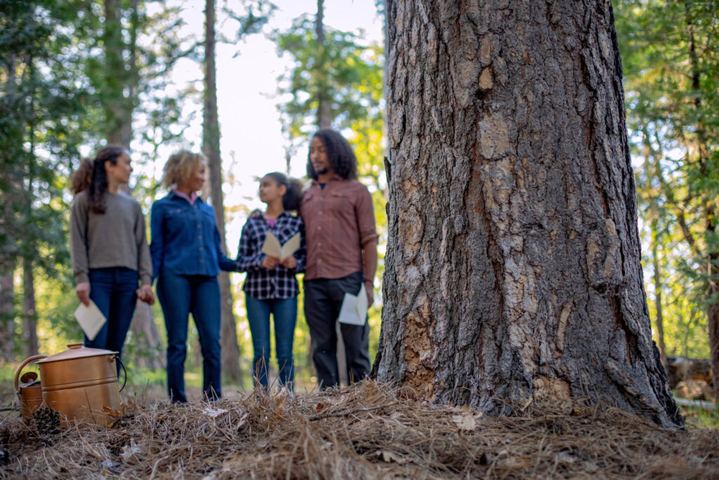 a family stands at a memorial tree after losing a parent