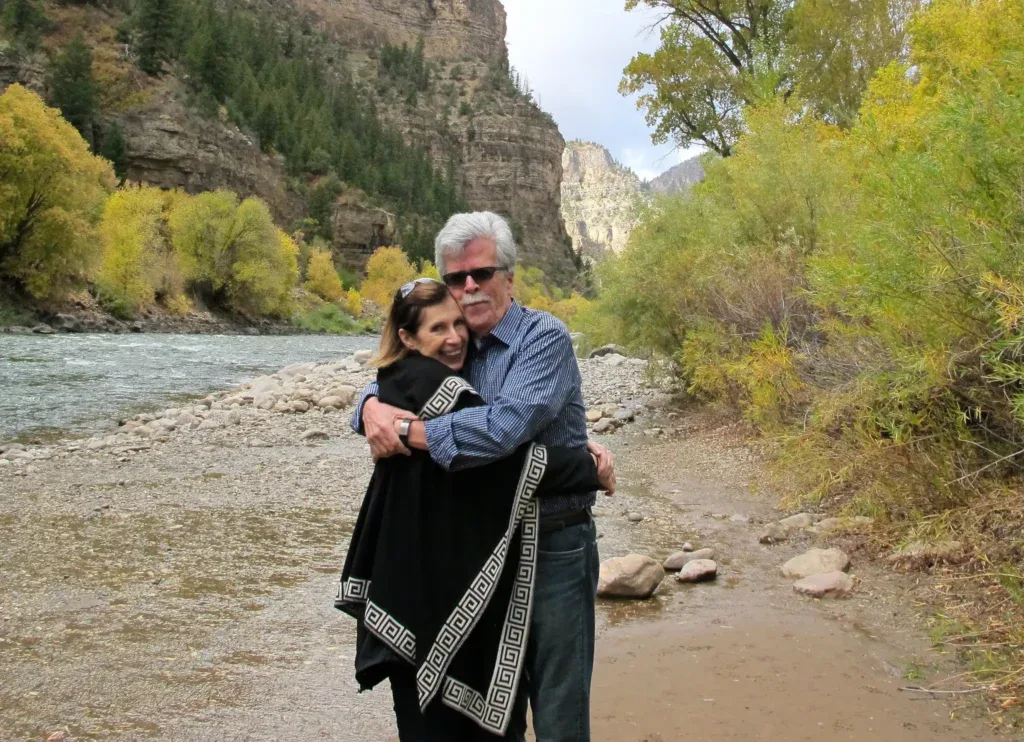 A couple hug near a river bed.