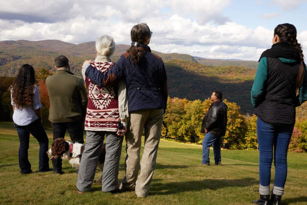 family stand together in a meadow. They can be support for end-of-life massage therapy