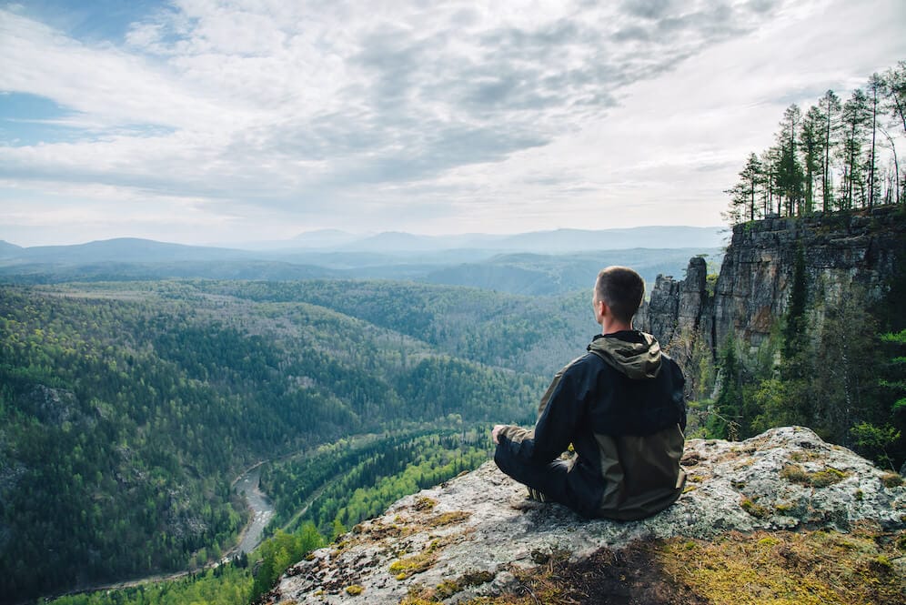 a man takes a solace moment looking over a valley dealing with grief over losing someone to suicide