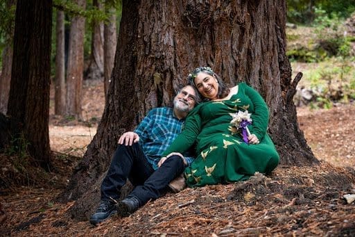 A couple sits on a redwood tree