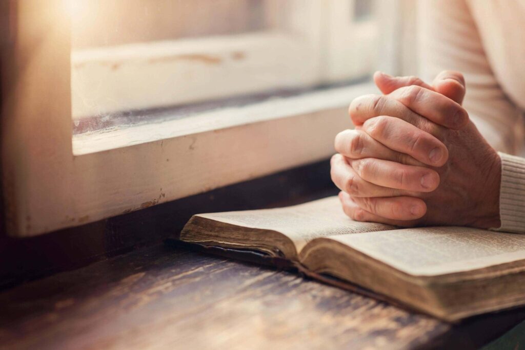 Hands praying over a bible