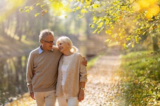 A man and woman walking along an outdoor path discussing senior resources and programs for the elderly