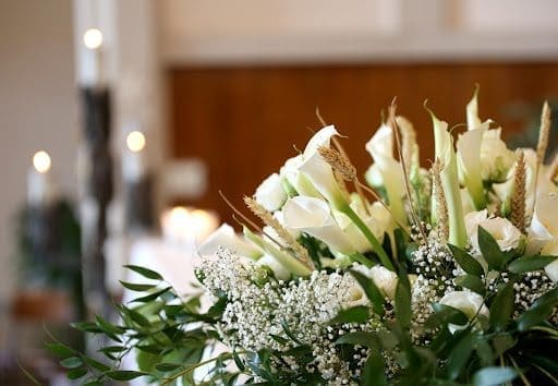 White flowers in a bouquet with candles in the background