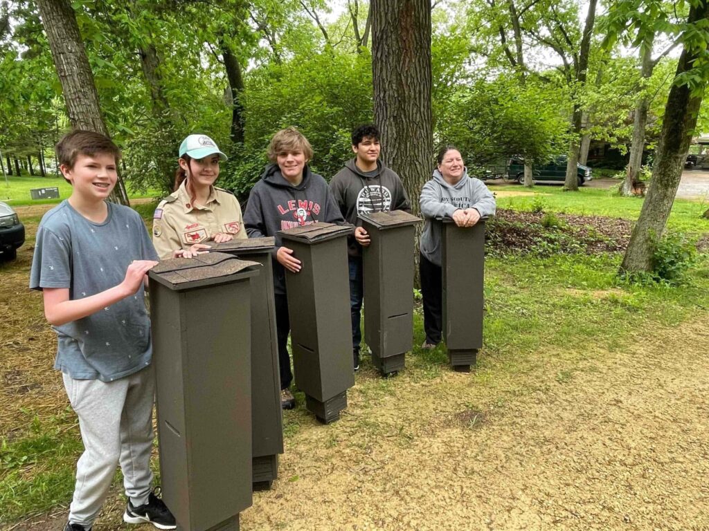 Four young people holding bat boxes in Better Place Forests Rock River