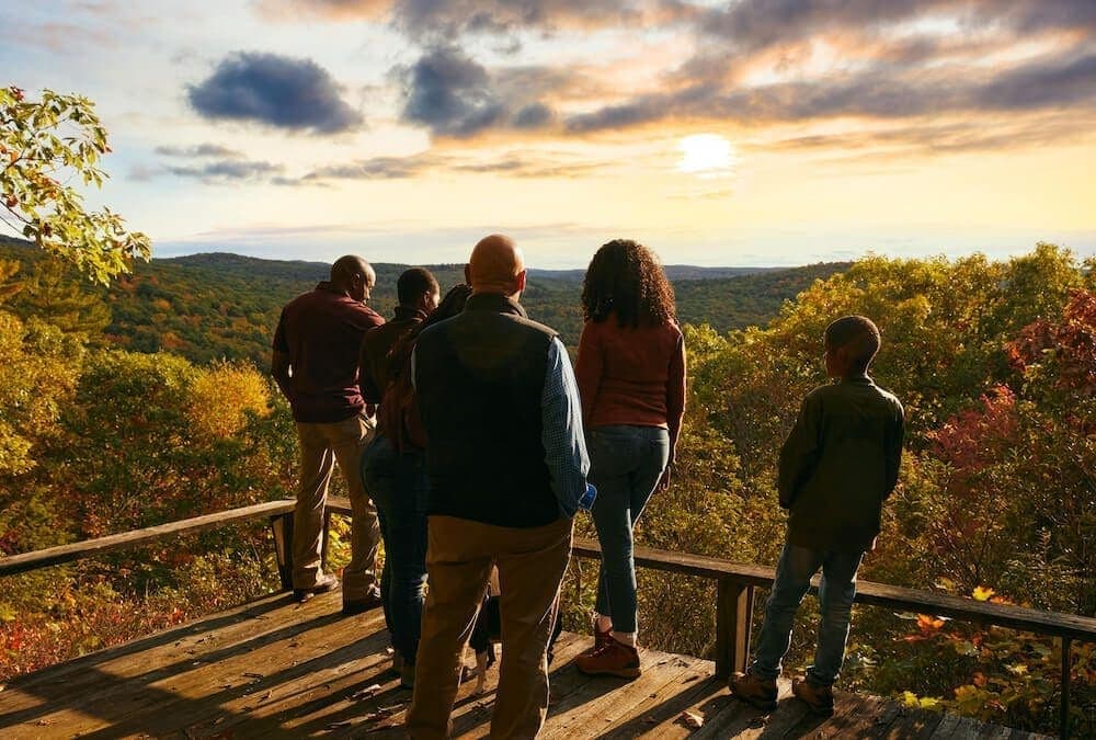 Family standing at an overlook enjoying the view of mountains and forest in the fall