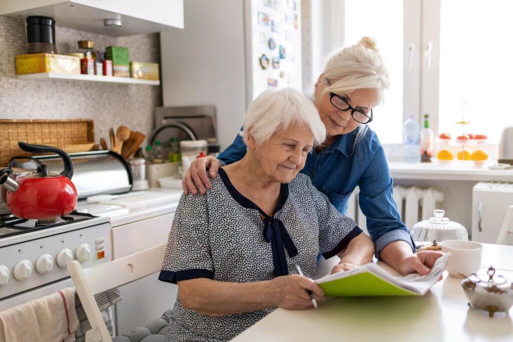 Two older women sitting at counter filling out forms together