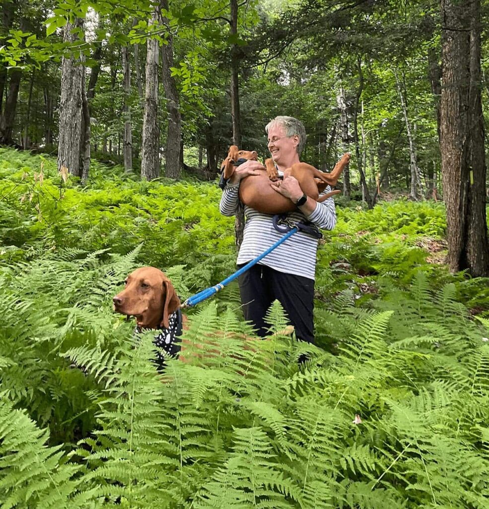 Diane holding her dogs in the forest. You can include your pets in your end-of-life plans