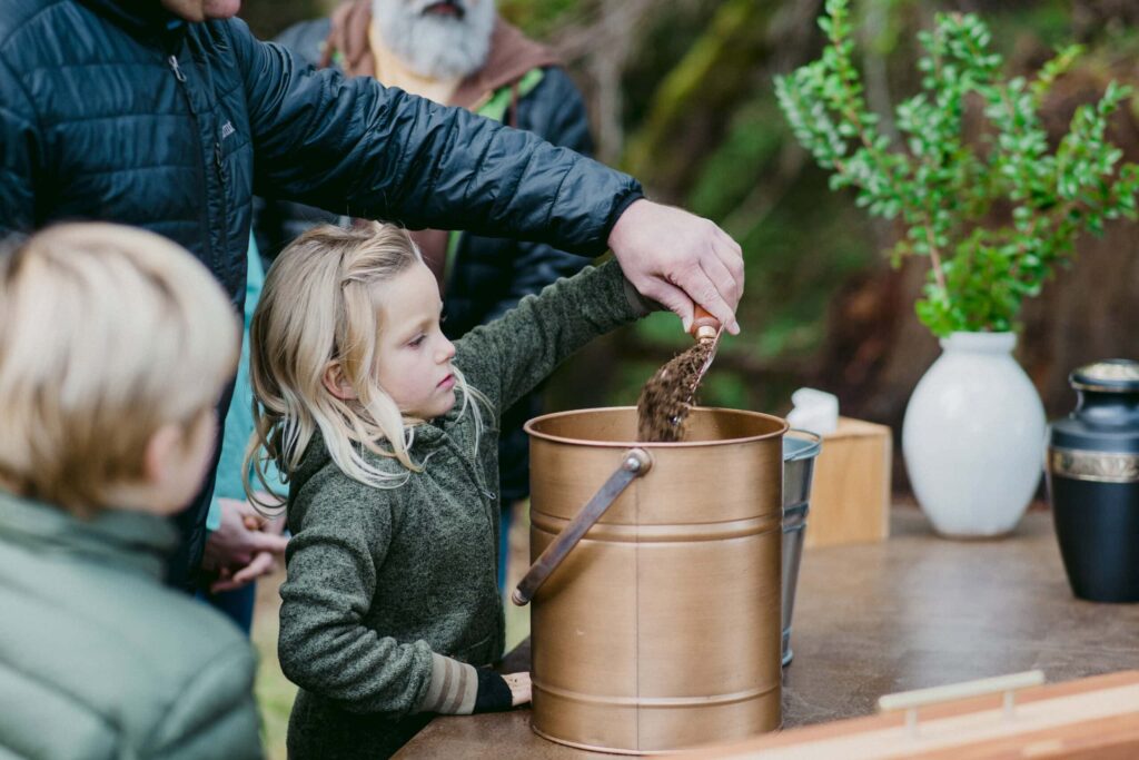 a girl helps her dad mix soil with ashes. They dealt with cremation cost