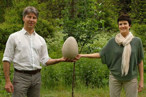 A photo of two people holding a prototype of a Capsula Mundi. An alternative to a memorial tree
