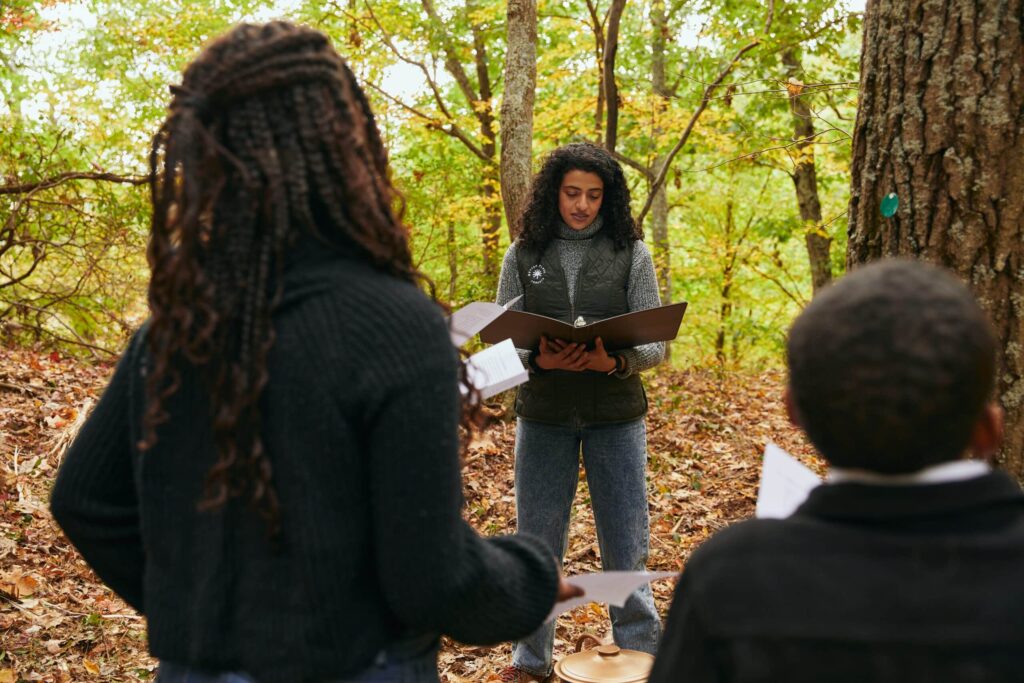 A woman in a memorial forest read an eulogy of someone who has passed to a group of family members during a forest memorial ceremony