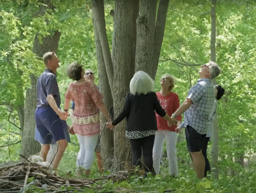 The Groves family holds hands in a circle around their memorial tree in better place forest memorial forest.