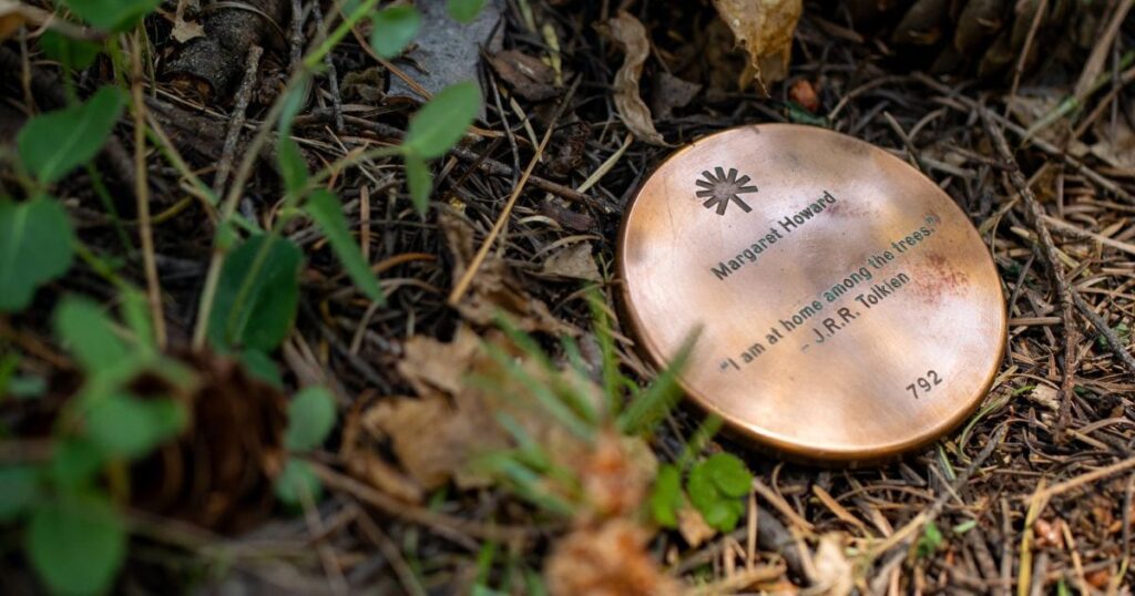 a bronze plaque at the bottom of a memorial tree shows why a memorial marker matters