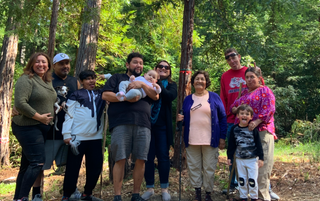 The multi generational Lombera family stands in front of their memorial tree in the Better Place Forests Santa Cruz Memorial Forest in California.