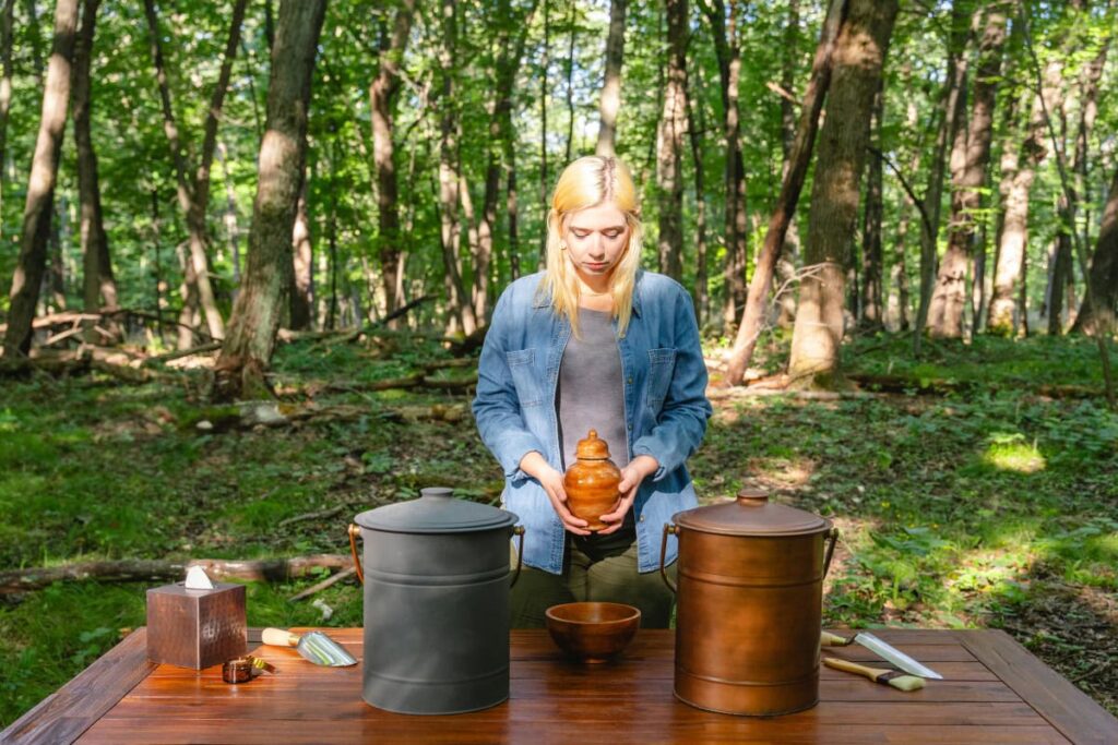 A woman holding an urn in the forest. She understands how to plan a funeral.