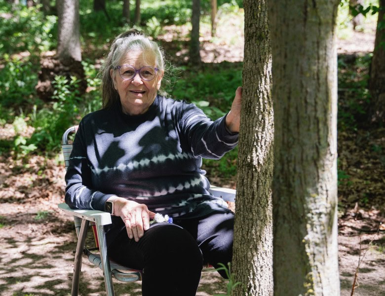 a woman sits by her husbands memorial tree in better place forests rock river memorial forest.