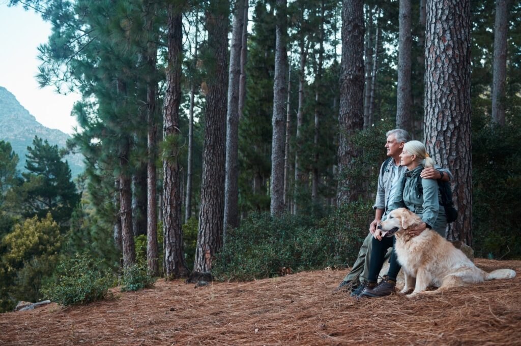 Senior couple with their beloved older pet standing in a memorial forest