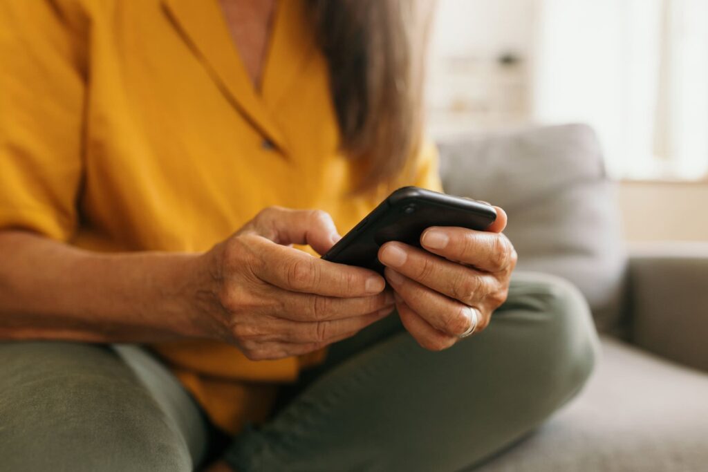 Elderly woman texting on mobile phone at home.
