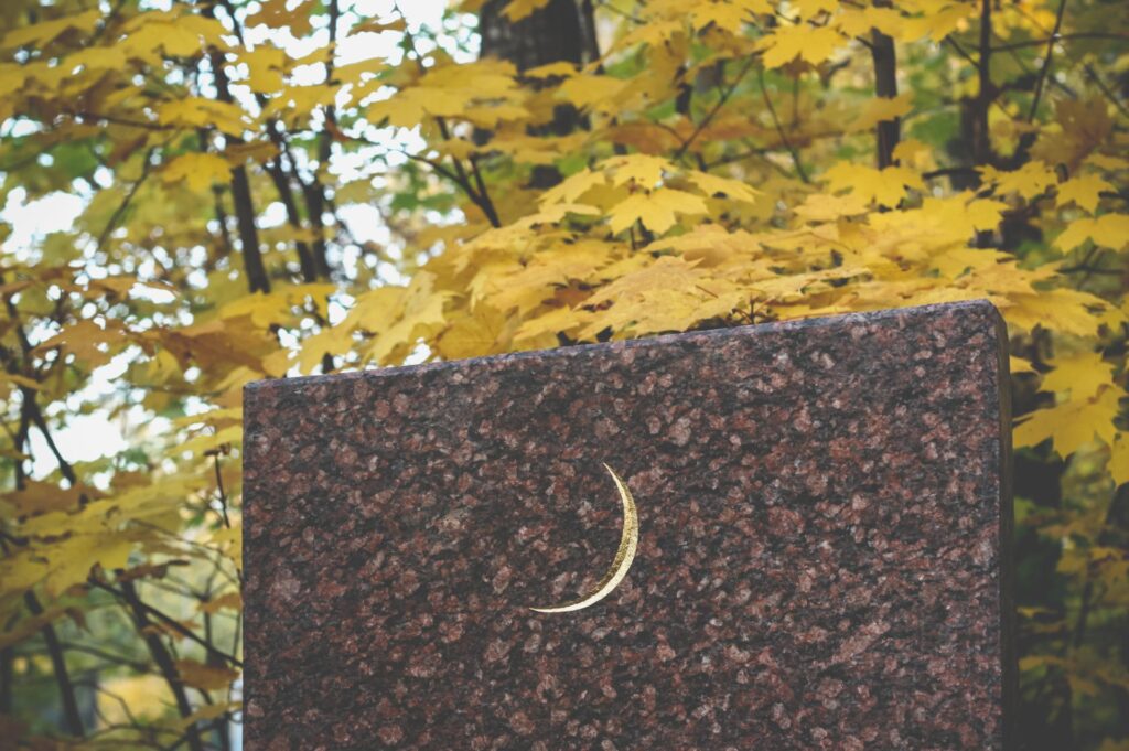 Golden muslim crescent moon on a granite tombstone.