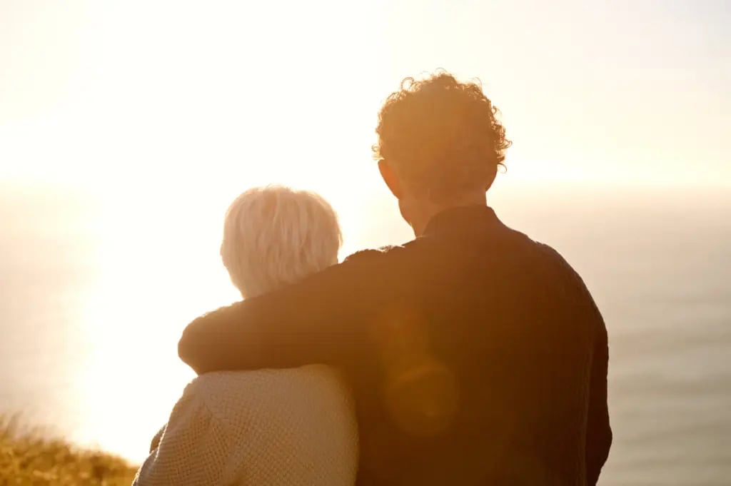 Older couple standing together looking at the sunset over the ocean